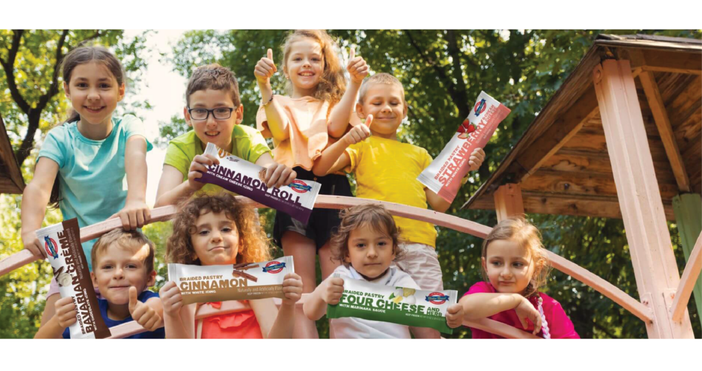 Group of elementary-aged school kids holding packages of Butter Braid® products outside.