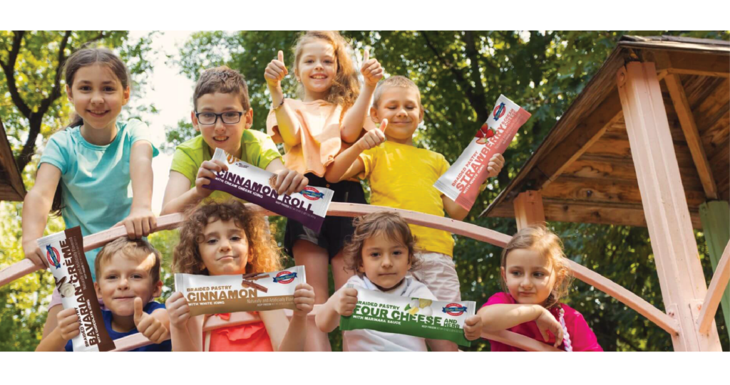 Group of elementary-aged school kids holding packages of Butter Braid® products outside.