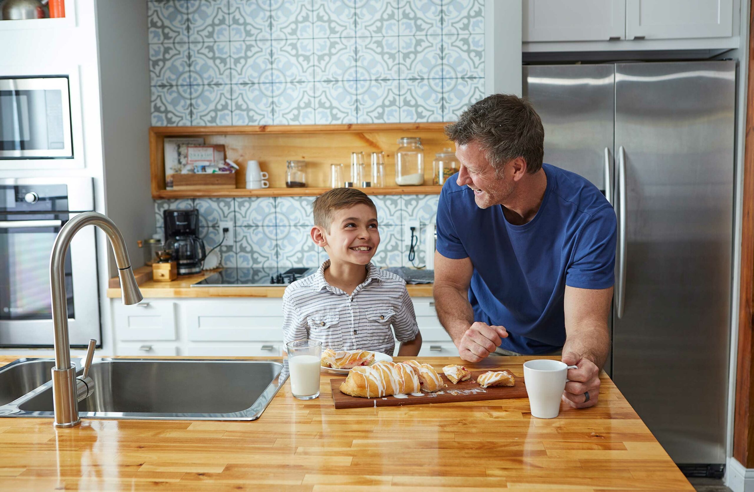 How to Get More Pastries? Dad and son with a Butter Braid Pastry, cut up, on platter and plate in front of them on the kitchen island.