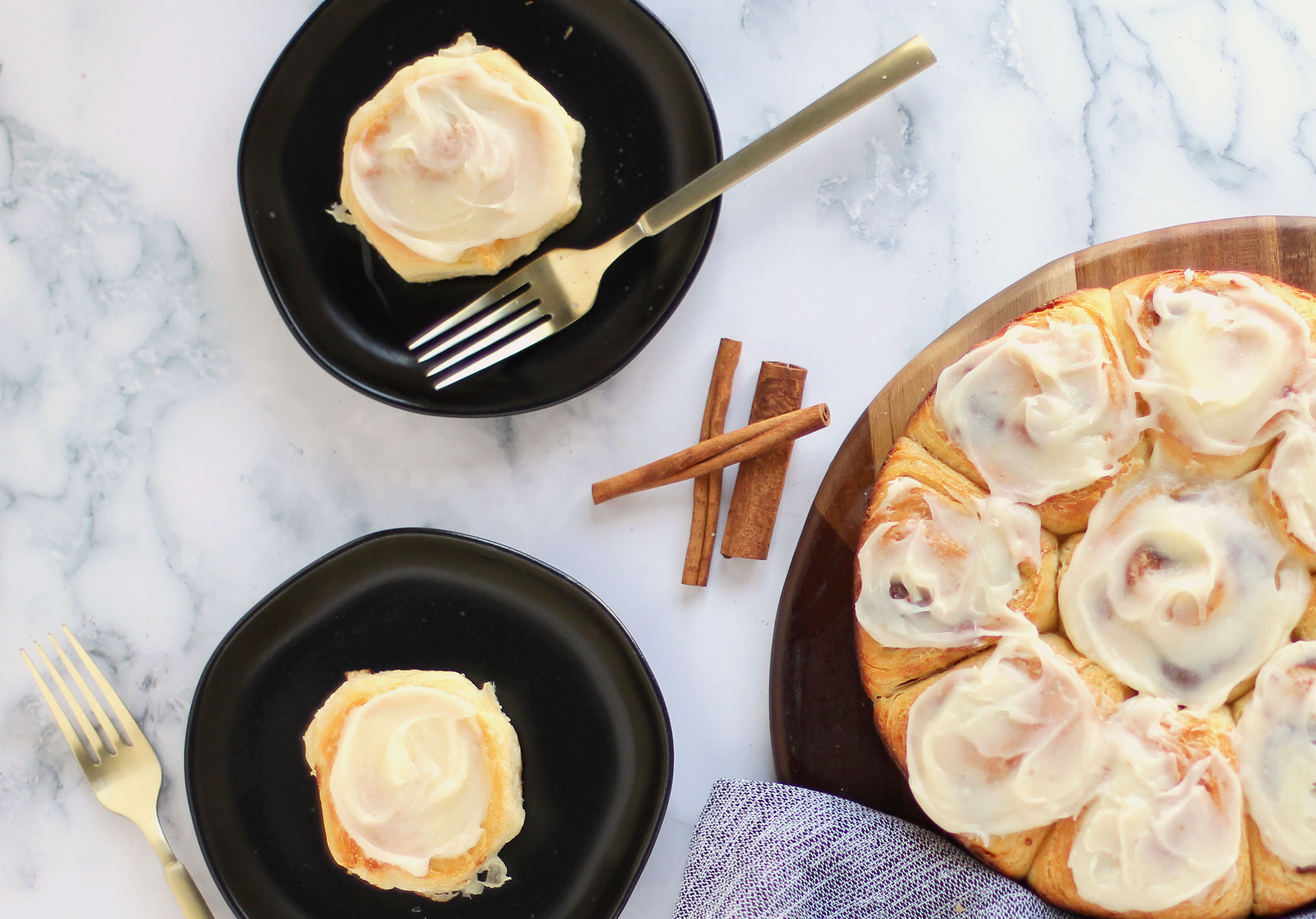 Cinnamon Pastry Rolls together on a serving platter with individual rolls on plates. Cinnamon sticks used as garnish.