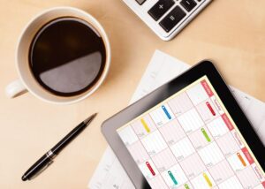 How Long Should Your Fundraiser Be? Desk close-up with cup of coffee, pen, calculator, and tablet with a calendar on it.