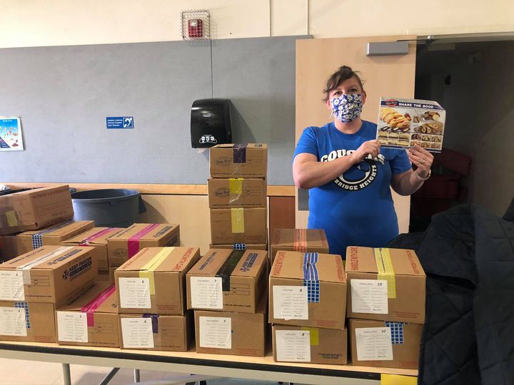 Group leader holding butter braid pastry order form in front of boxes of product in a classroom