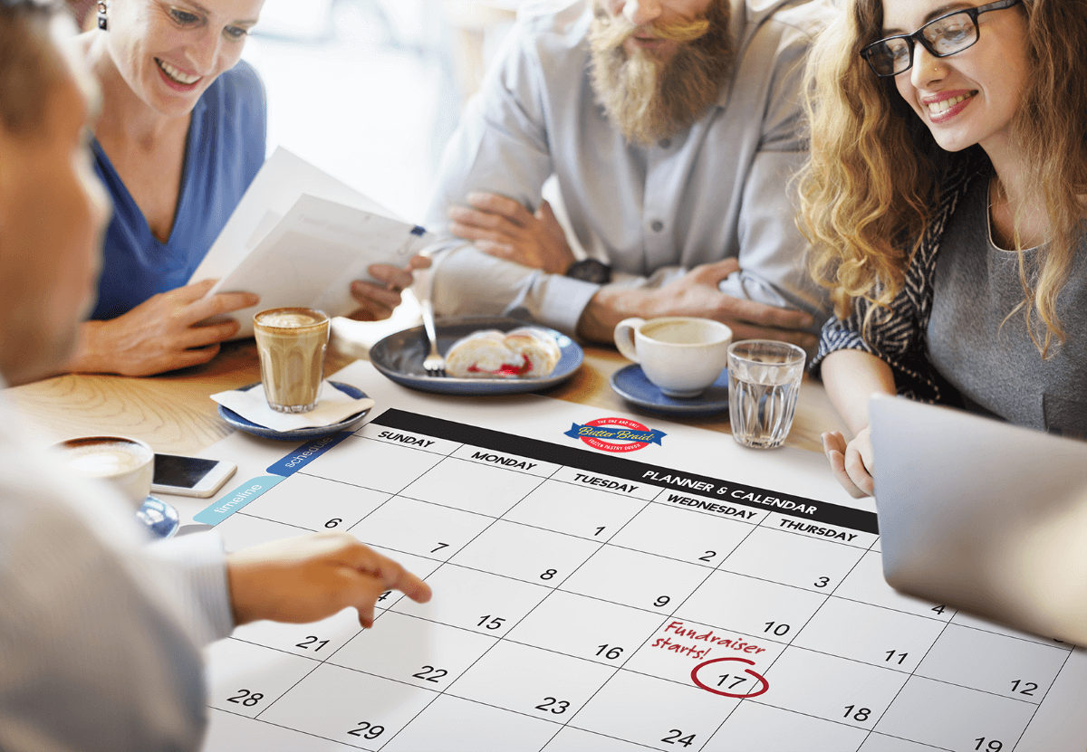 Tips for Your Next Fundraiser - group of people around a calendar with coffee and pastries talking about Butter Braid® Fundraising programs.