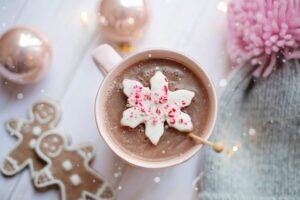 Hot cocoa cup surrounded by Christmas decorations and goodies