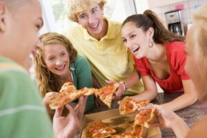Groups of teens eating pizza in a kitchen - fundraising incentives