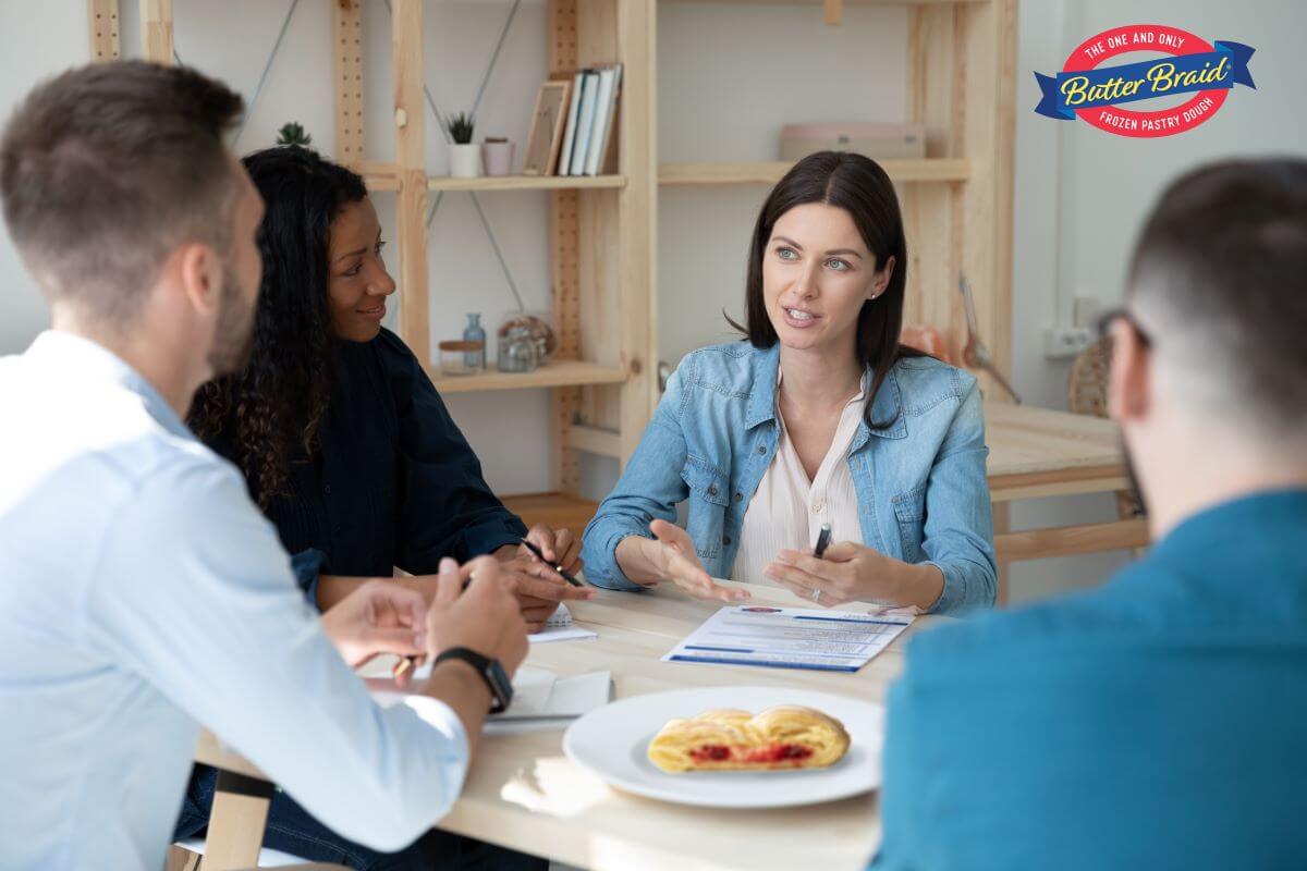 Tips on Finding the Right Fundraiser for Your Group main image - group of adults around a table evaluating fundraising options. A slice of pastry is also on the table.