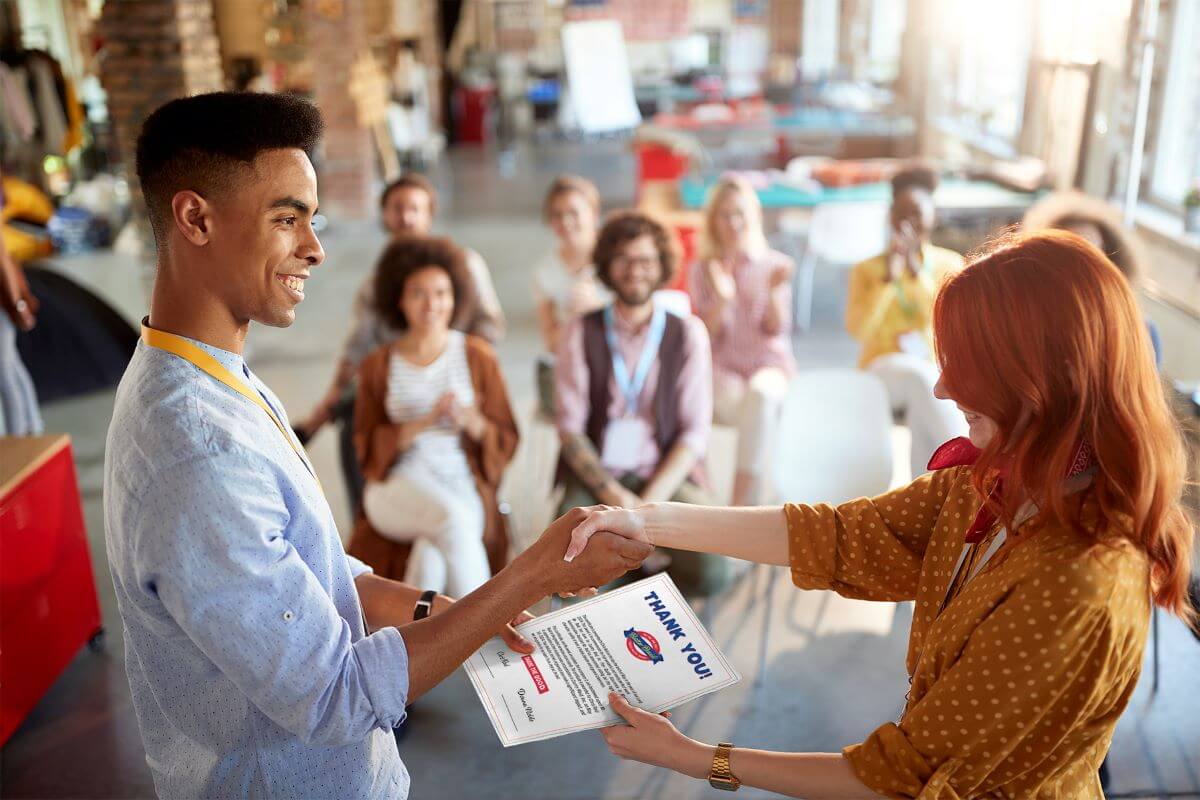 Strategy for Volunteer Retention: Show Your Appreciation - a woman giving a certificate to a man in front of a room of clapping people.