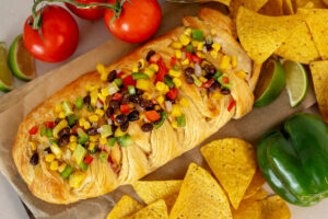 Raspberry Cowboy BBQ Pastry on a serving platter surrounded by tortilla chips, limes, peppers, and tomatoes.